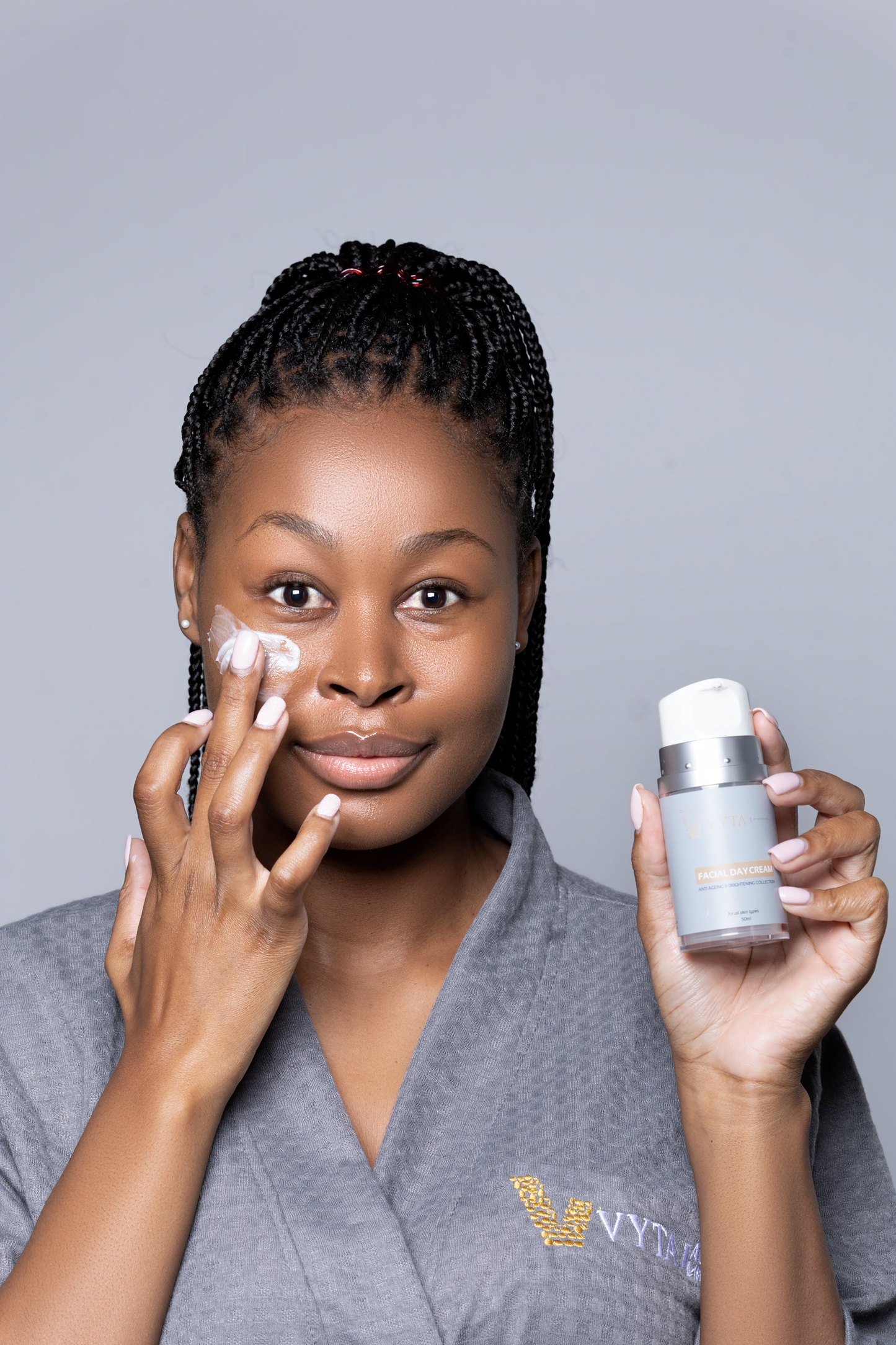 model with VYTA Aesthetics day cream on her face and holding pump bottle in her hand